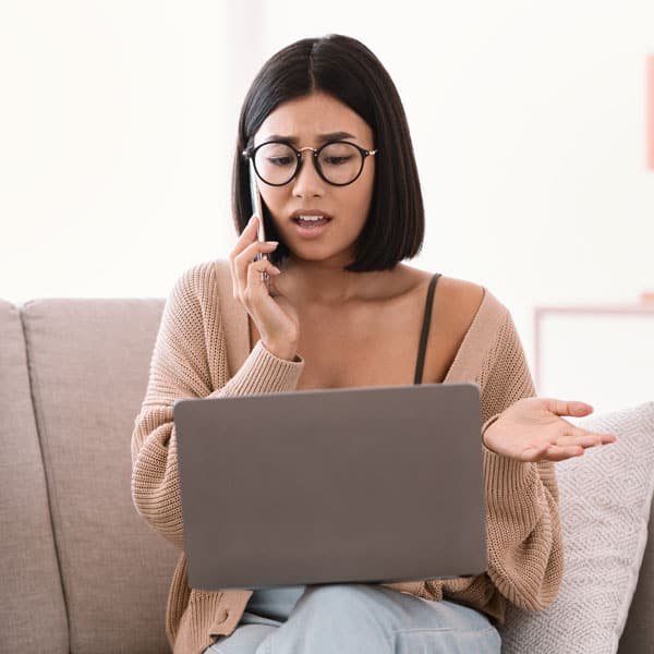 Frustrated woman seated on a couch talking on the phone