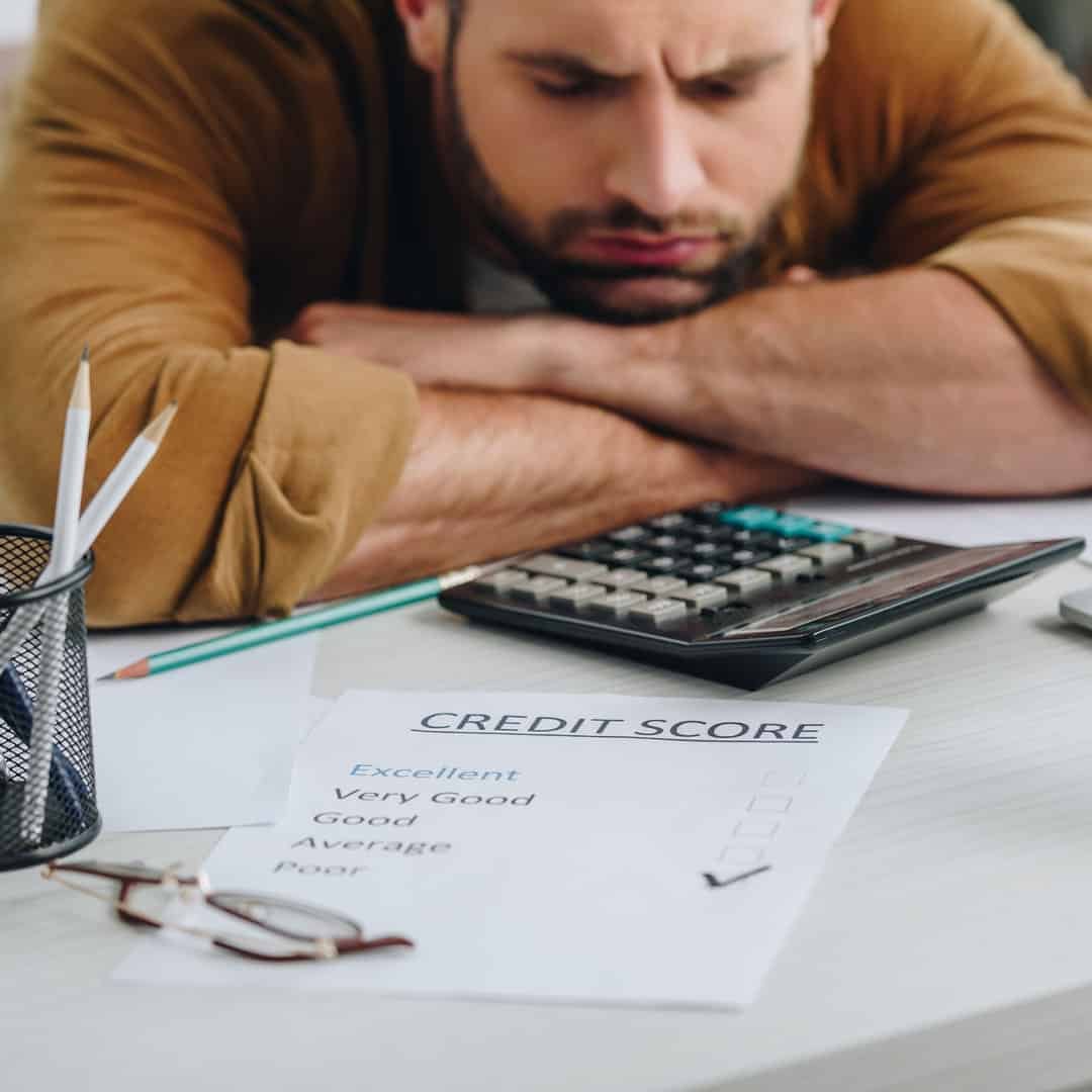 Frowning man seated at a table looking over a sheet of paper with a poor credit score