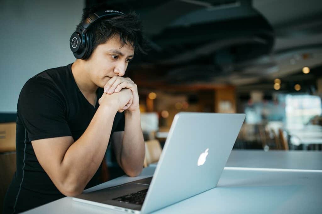 Man wearing headphones while sitting at a table in front of a laptop