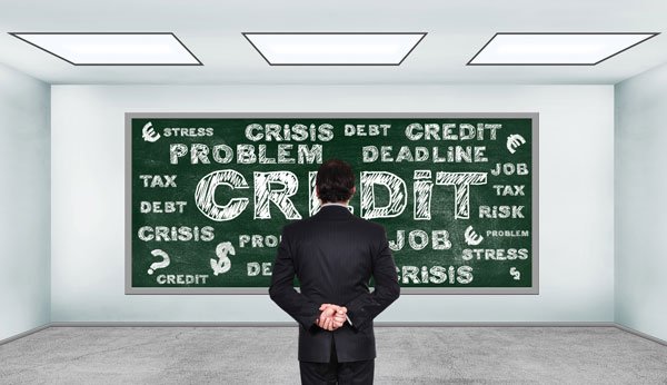 Man in a room facing a chalkboard written many credit-related words