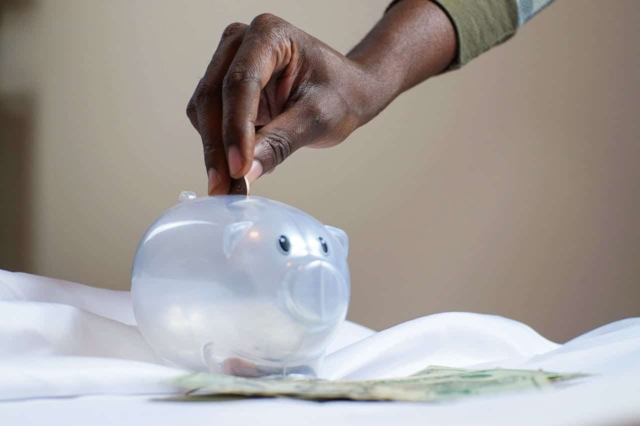 Person putting a coin into a piggy bank