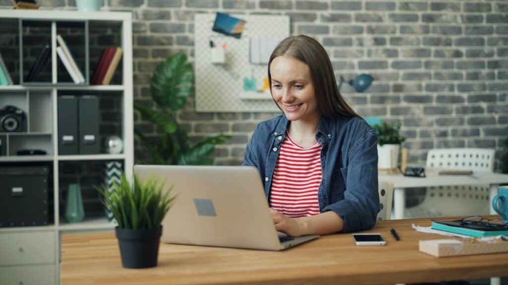 Woman seated at desk using a laptop to apply for a loan after credit loss