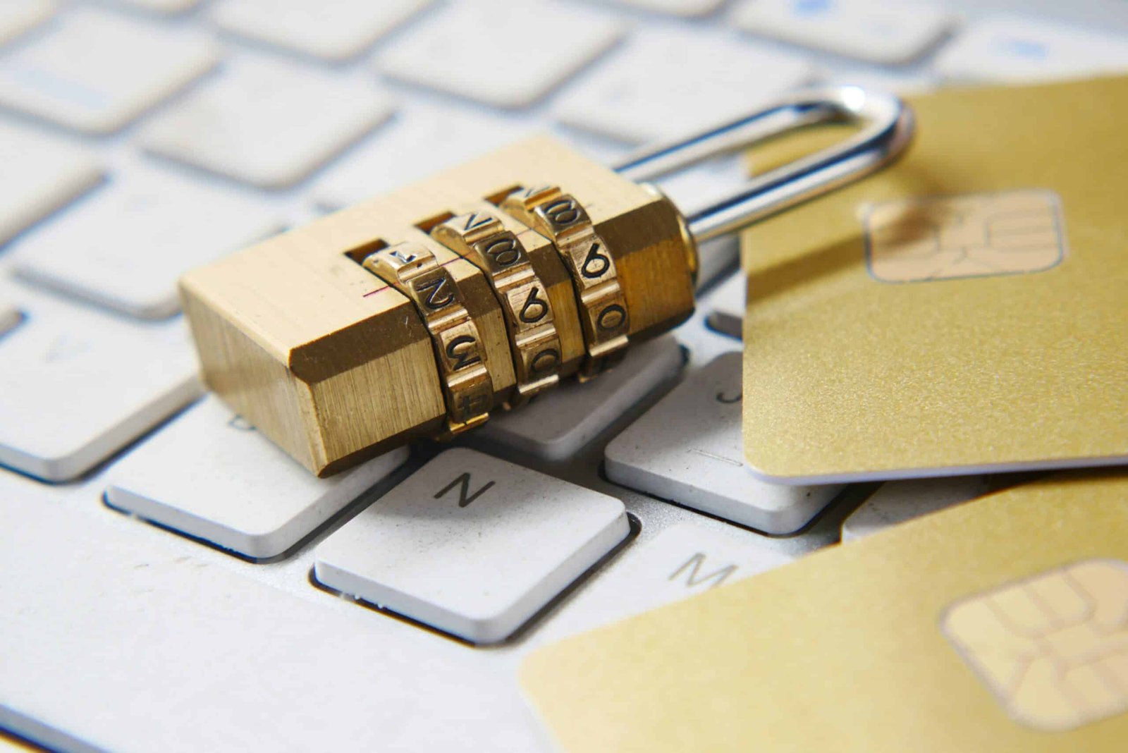 Golden padlock and golden cards lying on top of a laptop keyboard