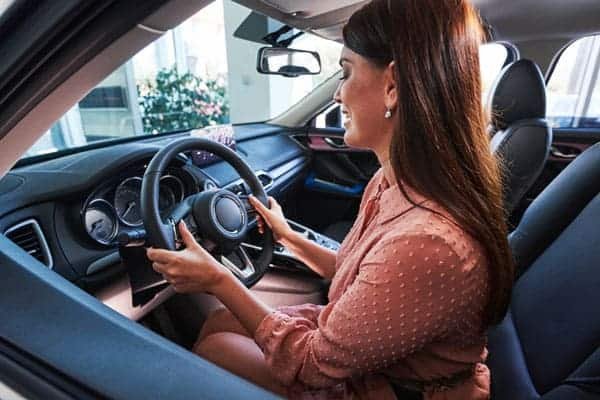 Lady sitting on the driver’s seat holding steering wheel