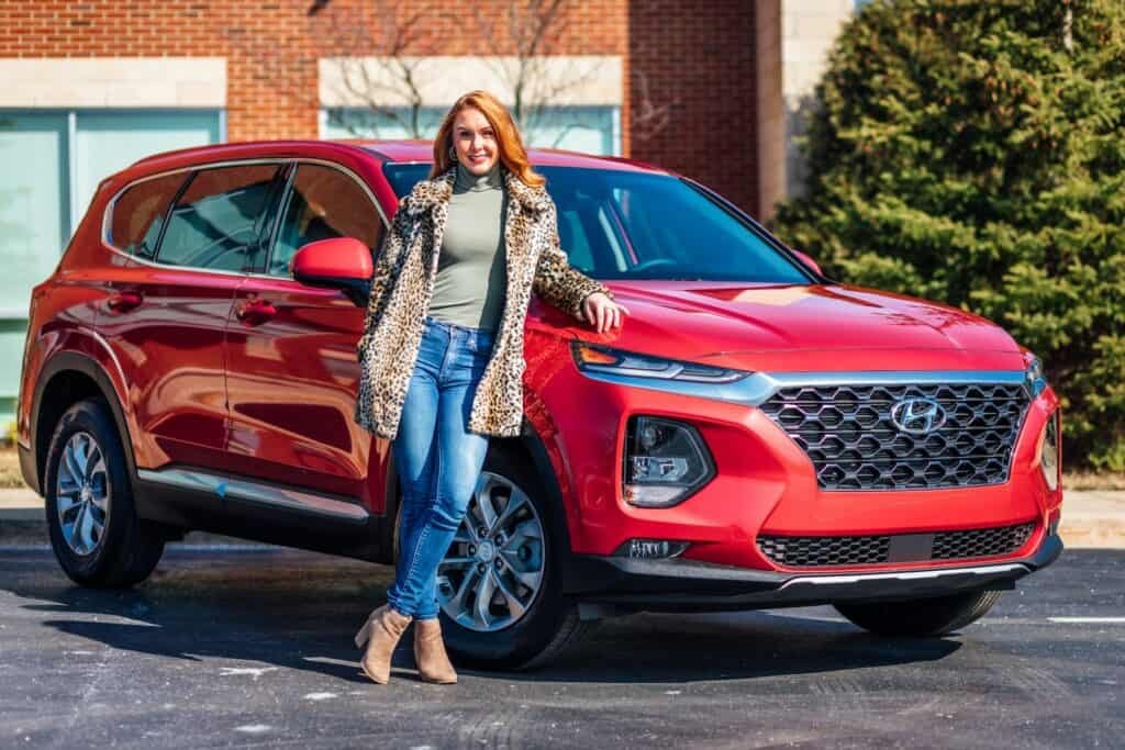 Woman leaning against a new car