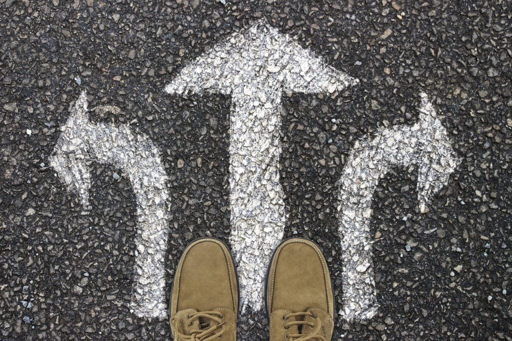 Feet facing three direction arrows on pavement