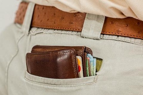 Leather wallet in man’s back pocket with debit cards and cash in it