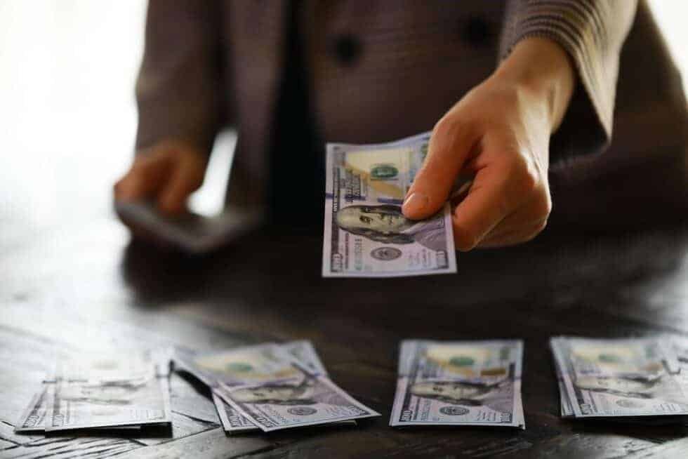 Person counting dollar banknotes placing them in small batches on a table