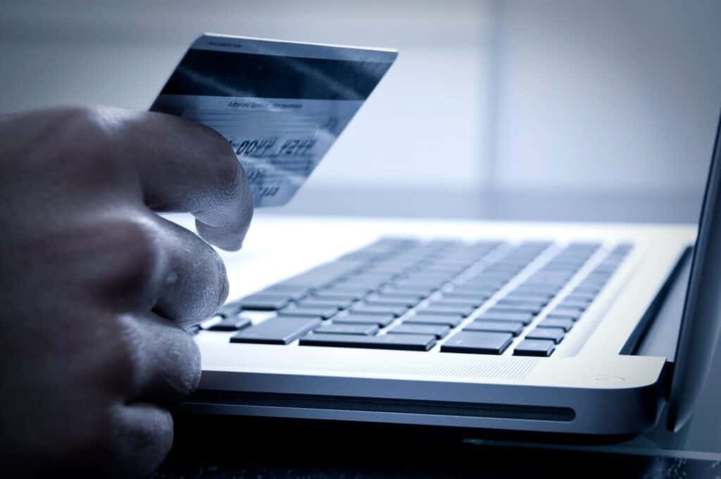 Hand holding a card next to a laptop